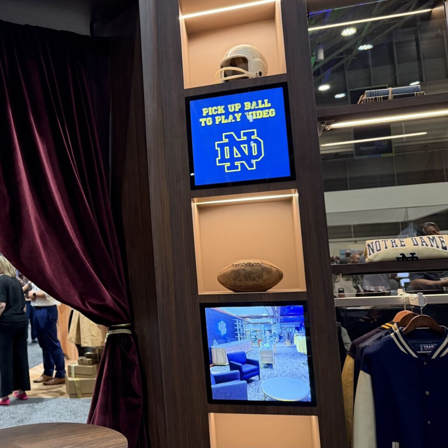 Two square LCD displays built into a wooden retail display column at a sports brand booth