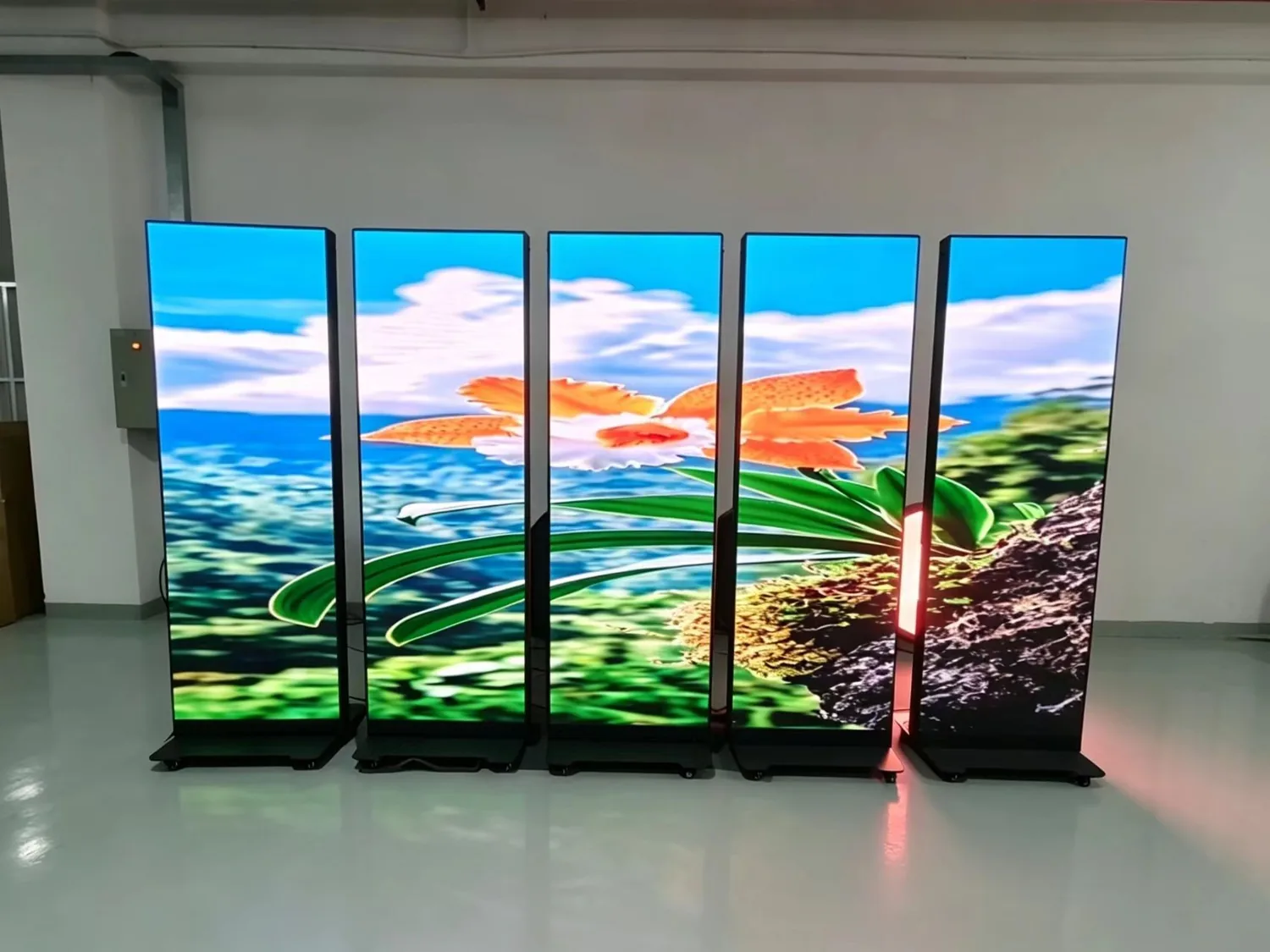 Five LED posters cascaded side by side in the factory, displaying one continuous flower image